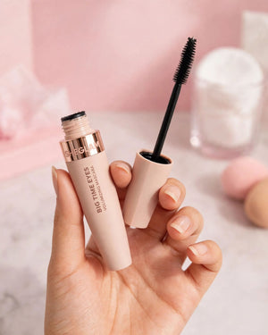 Close-up of hand holding open SHEGLAM Big Time Eyes Volumizing Mascara tube and wand showing black formula texture