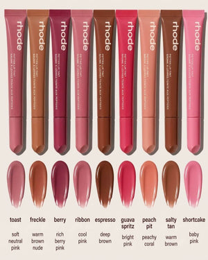 A row of Rhode lip gloss tubes in various shades, displayed above corresponding glossy swatches with shade names and descriptors on a pink background.
