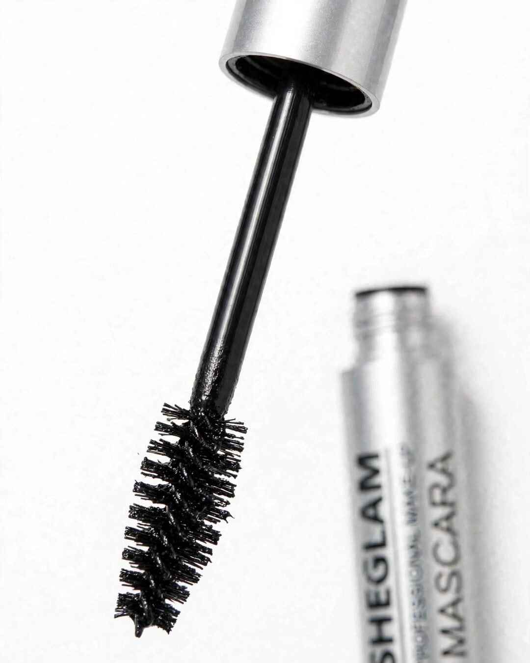 Close up of SHEGLAM Big Time Eyes olive shaped mascara brush wand with longer real life black stem and thick non-caking jet black formula - silver cap - shows unique brush that separates and lifts lashes